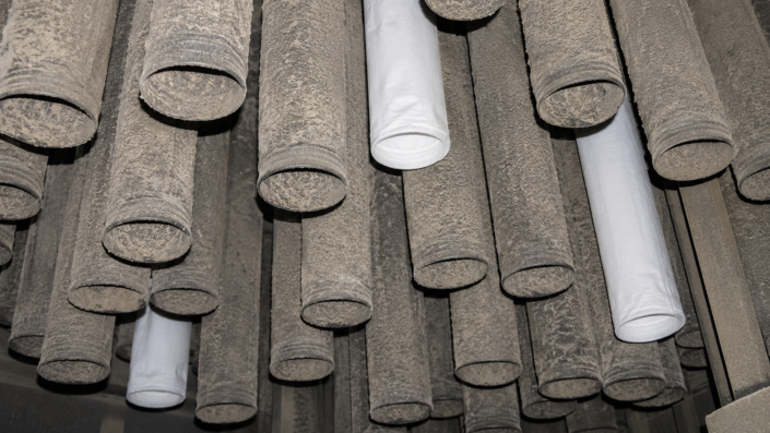 Should I Change All My Filter Bags or Spot change? Inside an industrial baghouse showing mostly dirty filter bags with three new replacement filter bags installed among them during maintenance.