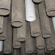 Inside an industrial baghouse showing mostly dirty filter bags with three new replacement filter bags installed among them during maintenance.